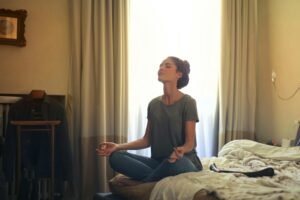 Woman in meditation pose on a bed